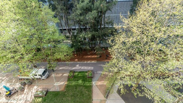 An aerial view of a parking lot with a truck, a green lawn, and trees. - Modern 2BR APT in Highgate Executive Apartment (Canberra)