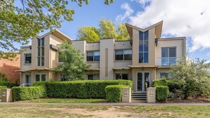 A modern two-story house with a symmetrical facade, large windows, and a well-maintained lawn.