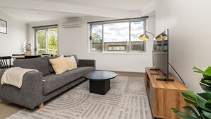 A modern living room with a grey sofa, a round coffee table, and a TV on a wooden stand.