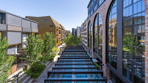 A modern building with a glass atrium, brick facade, and large windows. - Onyx Apt · Onsite EV Charger · 5mins to Foreshore (Kingston)