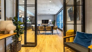 A modern interior with a dining area, a sofa, and a large window. - Onyx Apt · Onsite EV Charger · 5mins to Foreshore (Kingston)