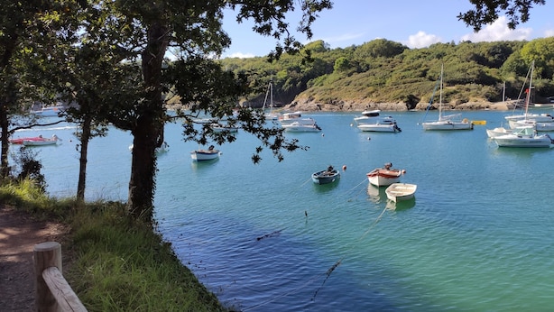 A marina with multiple boats docked, surrounded by lush greenery and hills. - Appartement Accueillant Tout Proche mer (Clohars-Carnoët)
