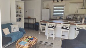 A compact living space with a sofa, coffee table, and a kitchenette area including a refrigerator and microwave. - Appartement Accueillant Tout Proche mer (Clohars-Carnoët)