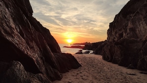 A rocky beach path leading to the sea with a sunset in the background. - Appartement Accueillant Tout Proche mer (Clohars-Carnoët)