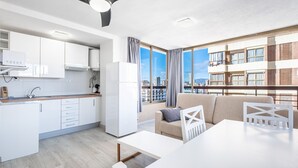 Ein modernes Apartment mit Küche, Essbereich und einem Balkon mit Blick auf die Stadt.