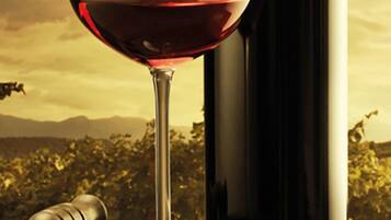 A wine bottle and glass on a barrel.