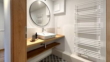 Un baño con un lavabo blanco, un espejo redondo y un suelo estampado.