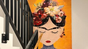 Un escalier avec une rampe et un mur orné d’une fresque florale.