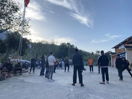 Una plaza pública con gente y motocicletas, rodeada de árboles y edificios.