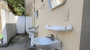 Un petit espace toilettes extérieur avec trois lavabos et une fenêtre.