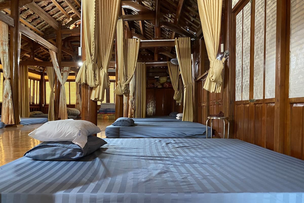 Una habitación con dos camas, cada una con ropa de cama y almohadas a rayas. La habitación tiene paredes de madera y un techo alto con vigas a la vista.