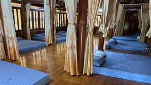 Une chambre avec plusieurs lits, un plancher en bois et des rideaux.