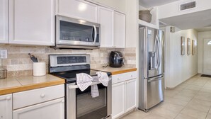 A modern kitchen with white cabinets, stainless steel appliances, and a wooden countertop.