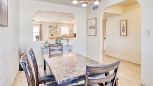 A dining area with a marble table and chairs, a chandelier, and framed artwork on the walls.
