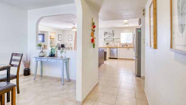 A spacious kitchen with modern appliances, a dining area with a wooden table and chairs, and a hallway leading to a living area.