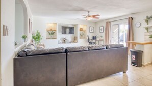 A modern living room with a large sectional sofa, a ceiling fan, and a dining area with a table and chairs.