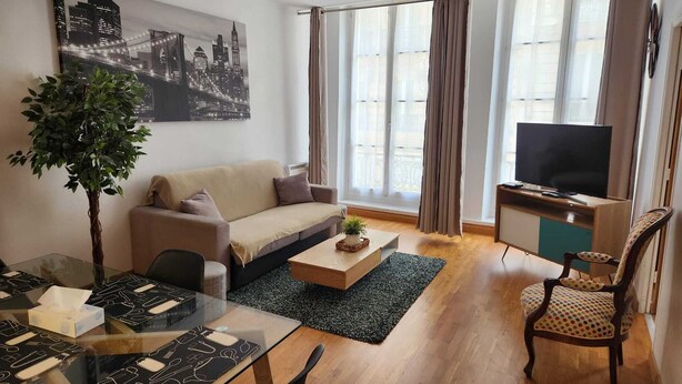 Un salon moderne comprenant un canapé, une table basse, un meuble pour la télévision et un coin repas avec une table et des chaises en verre.