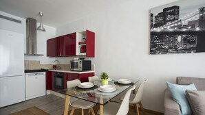 Une cuisine moderne avec des meubles rouges, une table à manger en verre et une vue sur le paysage urbain.