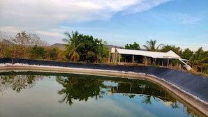 Ruhige Wasserfläche, die Bäume und ein Gebäude mit weißem Dach spiegelt.