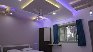 Ein Schlafzimmer mit einem Bett, einem Deckenventilator, einem Fenster mit Vorhängen und Einbauleuchten.