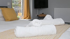 A hotel room with a bed, a TV mounted on the wall, and a window with curtains. - Modern en-suite room in country Pub/Restaurant (3) with communal kitchen - Pass the Keys (Llanddona)
