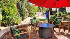 An outdoor patio with wicker furniture, a round table, and a red umbrella. - Private pool, spa, waterfall, firepit, BBQ, tennis, gym, hiking trails, casino (Palm Desert)