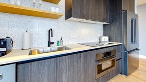 A modern kitchen with dark wood cabinets, a stainless steel refrigerator, and a built-in oven.
