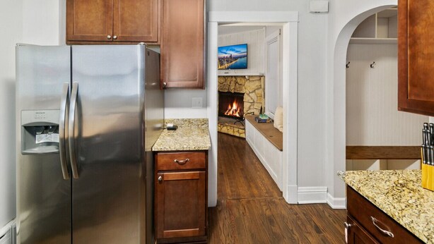 Una cocina moderna con refrigerador de acero inoxidable, armarios de madera, encimeras de granito y chimenea de piedra.