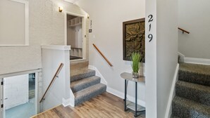Una escalera con barandilla de madera y peldaños alfombrados que suben a un segundo piso.