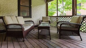 Un porche cubierto con muebles de mimbre y una mesa de vidrio.