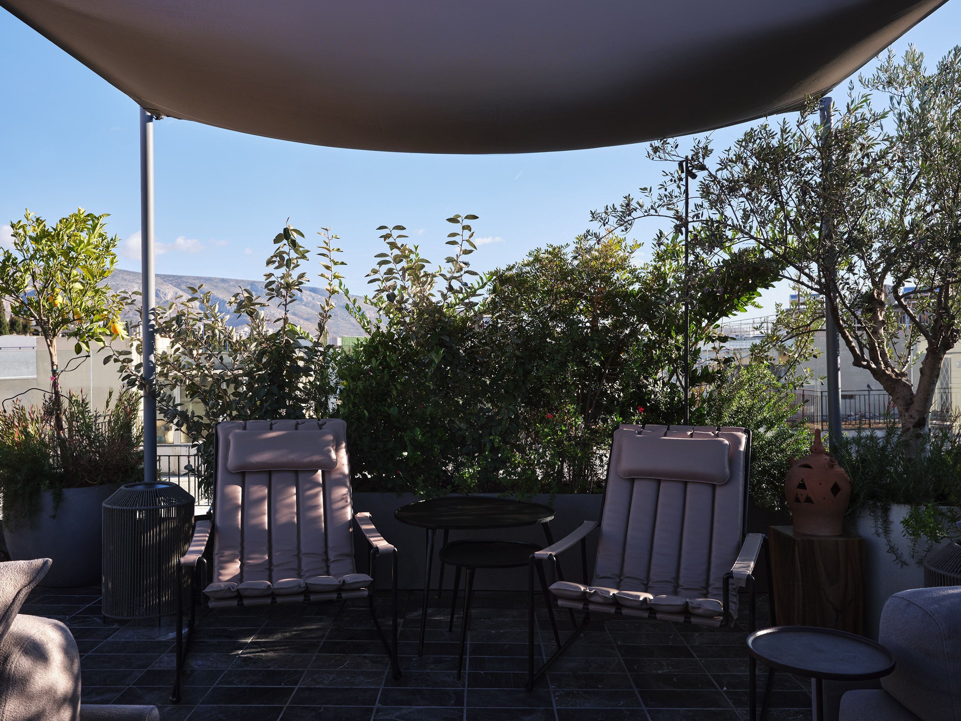 An outdoor patio with two cushioned chairs, a small round table, and a large umbrella providing shade.