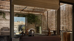 Un dormitorio moderno con una cama grande, vistas a un paisaje urbano y una planta decorativa.