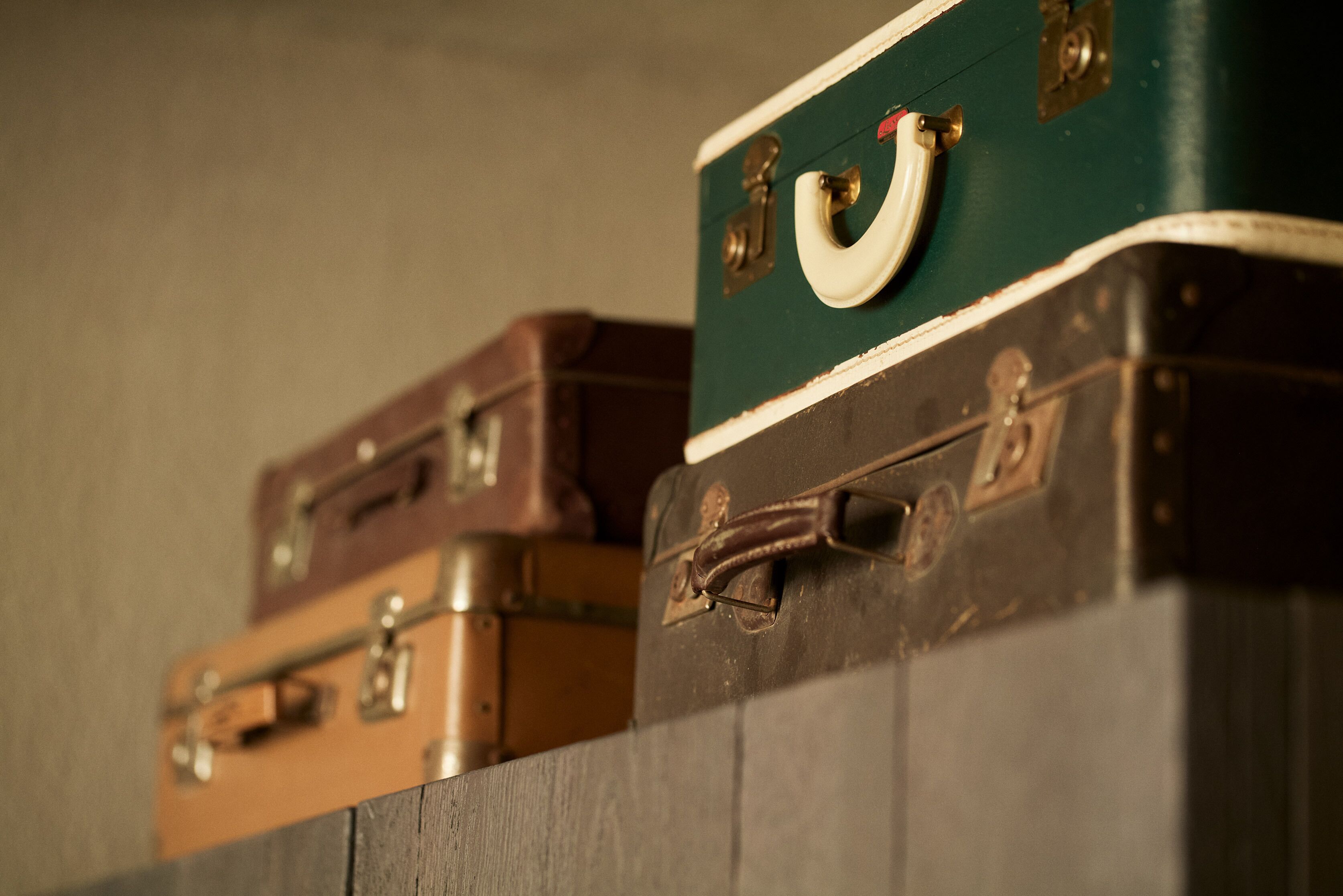 A row of vintage suitcases stacked against a wall.