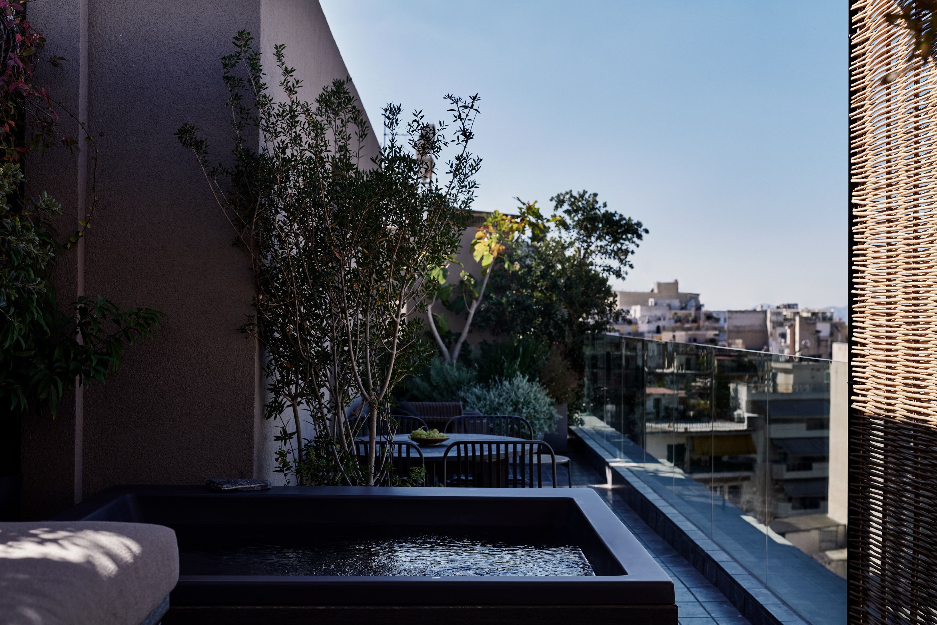 Una terrazza sul tetto con zona pranzo, un piccolo elemento d'acqua e vista sulla città.