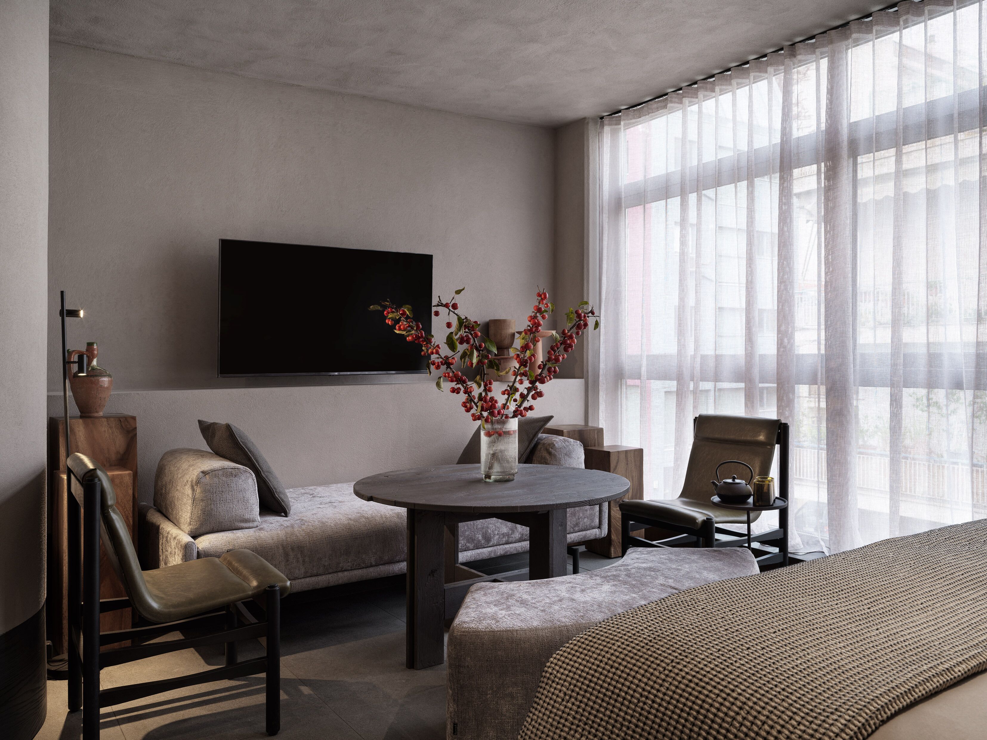 A modern living room with a sofa, a round table, and a TV mounted on the wall.