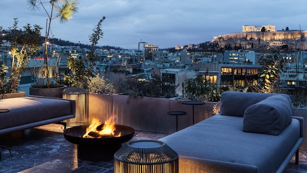 Terraza en la azotea con una chimenea, zona de estar y vistas a un paisaje urbano que incluye un edificio histórico.