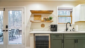 A kitchen with a built-in dishwasher, a coffee maker, and a window with blinds. - House on The Rocks with EV Charger (Chittenden)