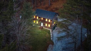 A cabin with a wooden exterior, a front porch, and a small yard. - House on The Rocks with EV Charger (Chittenden)