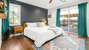 Un dormitorio con una cama grande, suelo de madera y un ventilador de techo.