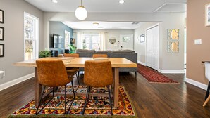 Un comedor moderno con una mesa de madera, dos sillas y una alfombra colorida.