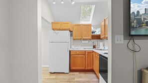 A modern kitchen with wooden cabinets, a white refrigerator, and a cityscape view. - Apt W/ heated garage Libertyville Near Naval Base (Libertyville)