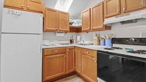 A kitchen with wooden cabinets, a white refrigerator, a stove, and a sink.