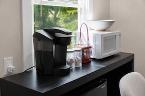 A kitchen counter with a coffee maker, a microwave, and a red basket containing kitchen items.