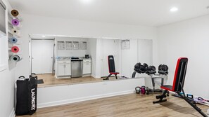 A gym with exercise equipment, a mirror, and a kitchen area. - Apt W/ heated garage Libertyville Near Naval Base (Libertyville)
