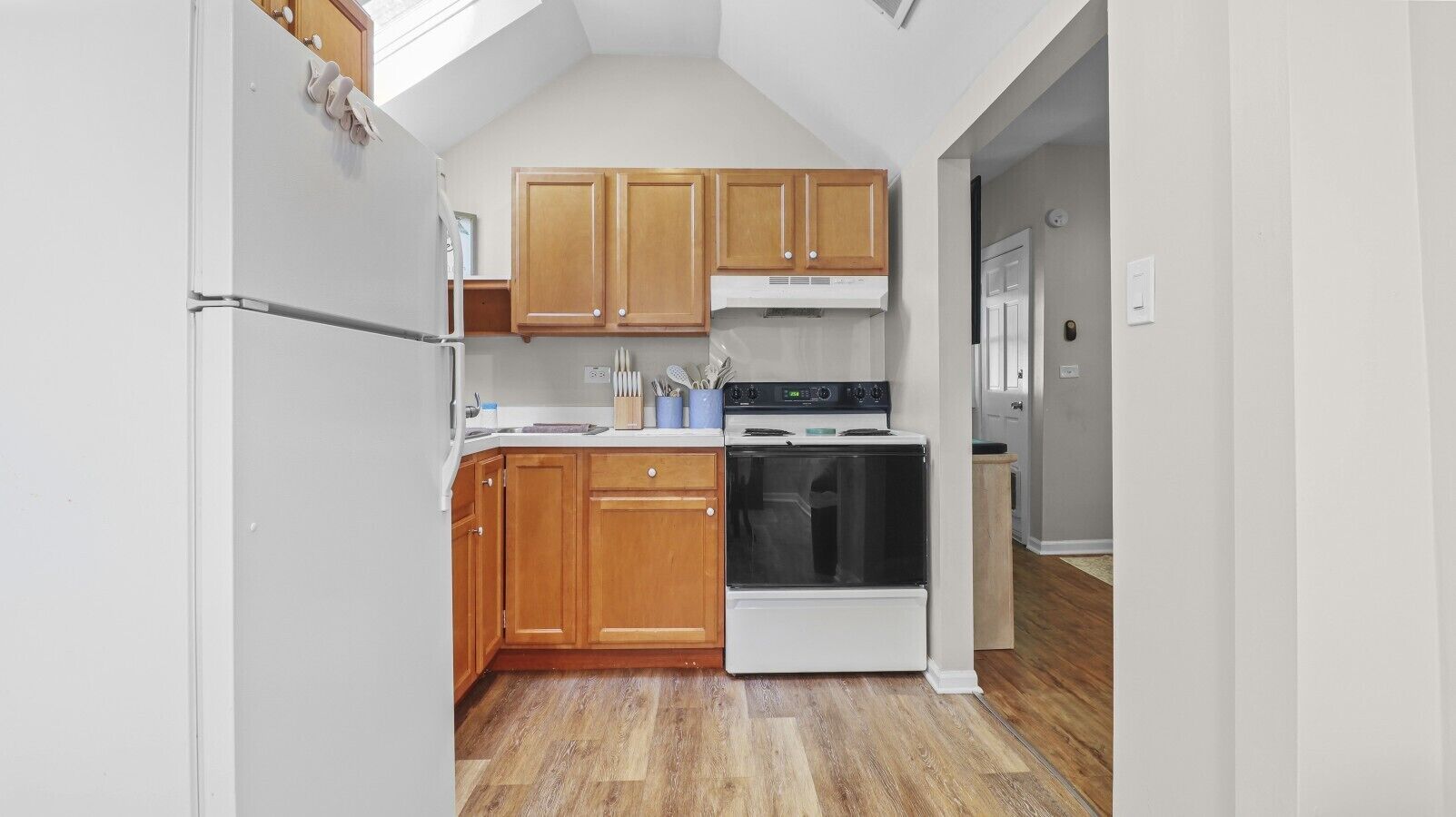A kitchen with wooden cabinets, a white refrigerator, a stove, and a microwave.