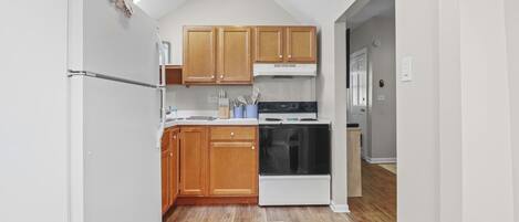 A kitchen with wooden cabinets, a white refrigerator, a stove, and a microwave.