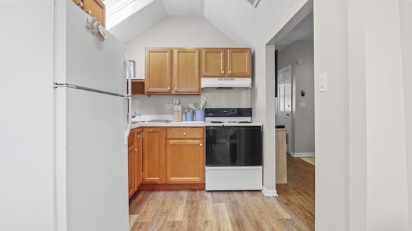 A kitchen with wooden cabinets, a white refrigerator, a stove, and a microwave.