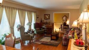 Una sala de estar acogedora con un piano, un sofá, una mesa de comedor y una silla.