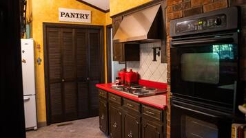 A kitchen with a red countertop, a black oven, and a pantry door.
