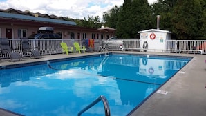 A swimming pool with lounge chairs, a lifebuoy, and a small building with a chimney.